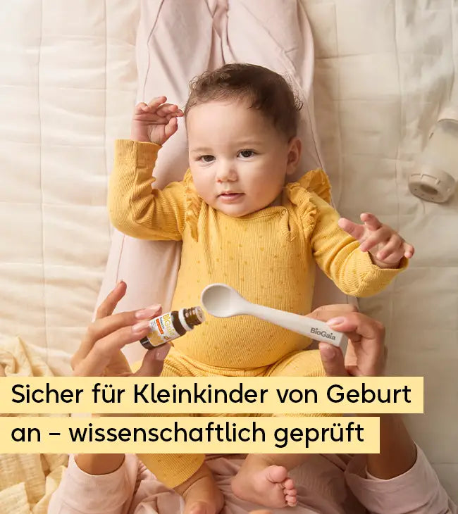 Ein Baby liegt entspannt auf dem Schoß eines Elternteils, während die BiGaia Tropfen auf einen Löffel gegeben werden. Text: Sicher für Kleinkinder von Geburt an – wissenschaftlich geprüft.