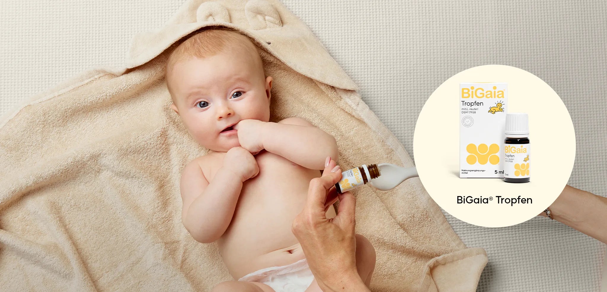 Ein Baby liegt nach dem Baden auf einem Handtuch, während ein Elternteil die BiGaia Tropfen auf einen Löffel gibt.