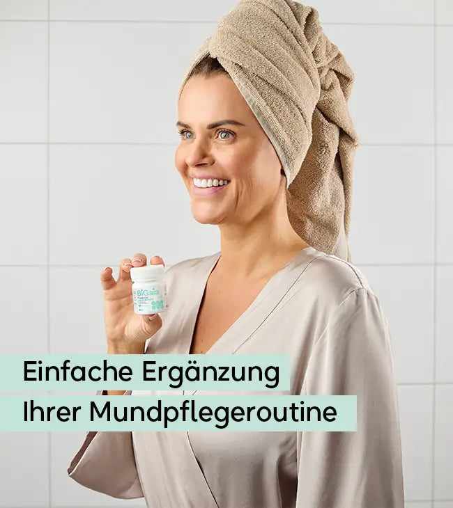 Eine lächelnde Frau mit Handtuch-Turban hält die BiGaia Prodentis Fresh Breath Dose neben ihr Gesicht. Text: Einfache Ergänzung Ihrer Mundpflegeroutine.