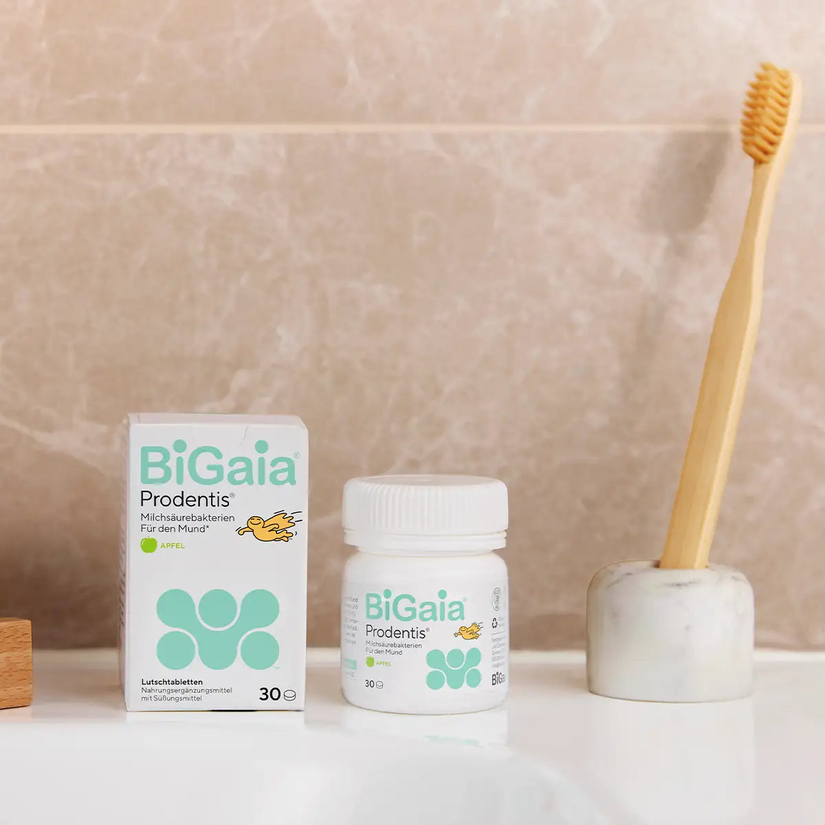 BiGaia Prodentis Apfel Packung und Dose neben einer Bambuszahnbürste im Badezimmer.