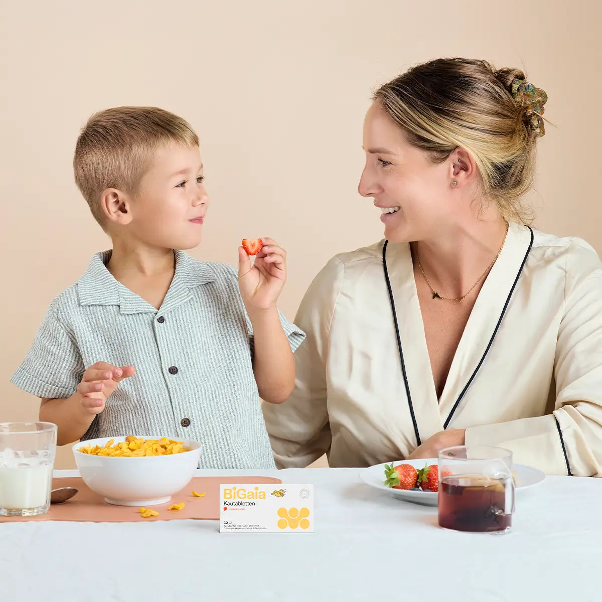 Ein kleiner Junge und seine Mutter am Frühstückstisch mit einer Packung BiGaia Protectis Kautabletten.